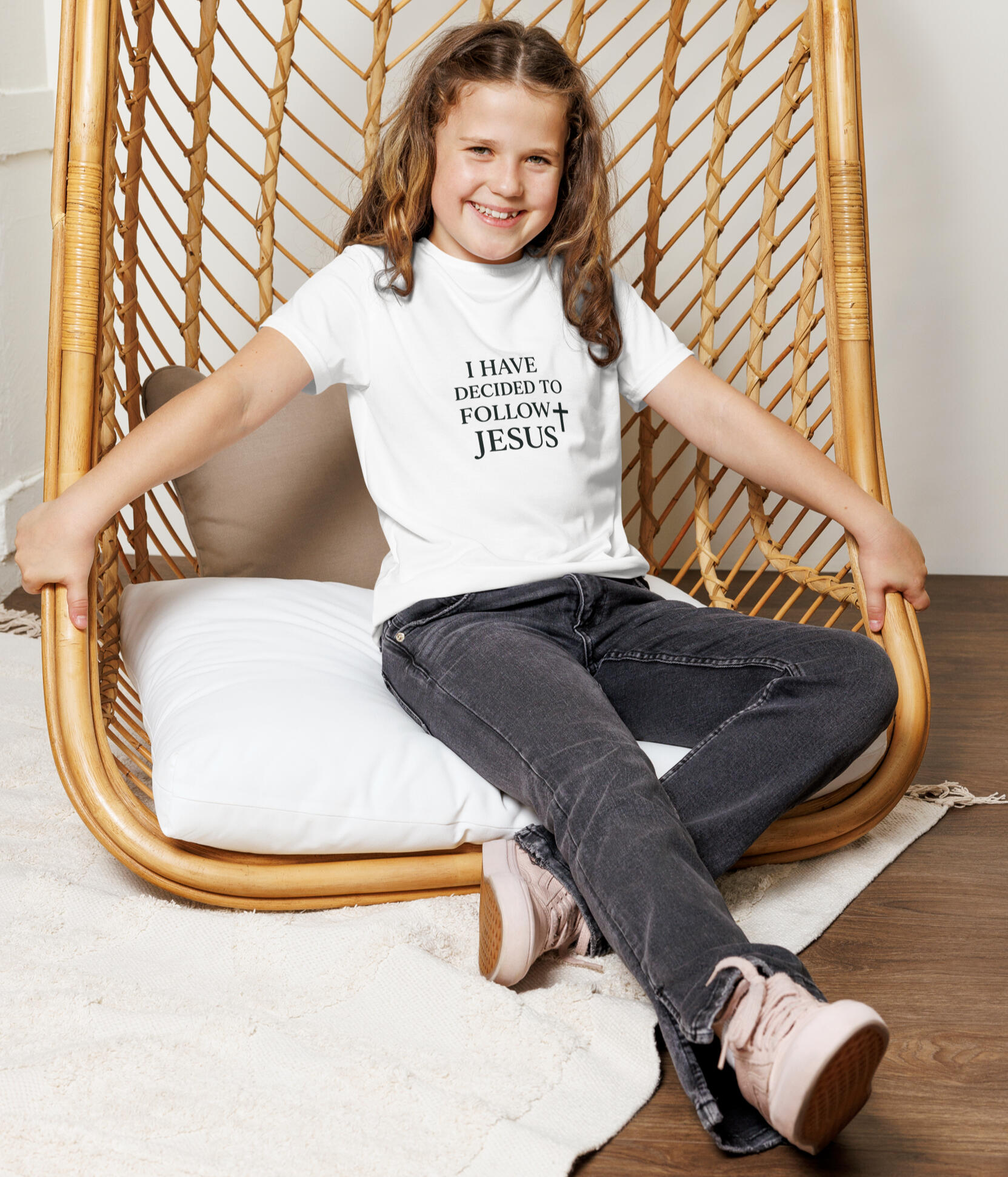 Girl on an indoor swing wearing the, "I Have Decided to Follow Jesus" white tee shirt by Tela Designs Store